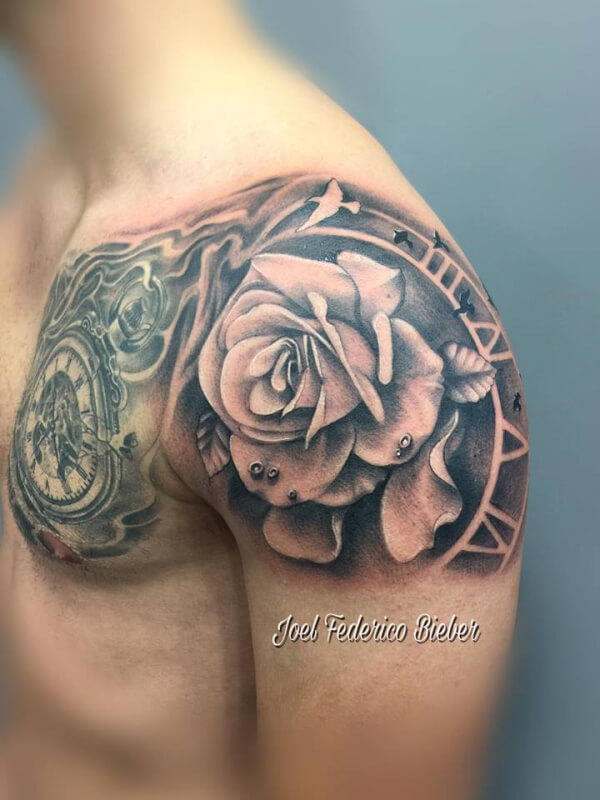 Realismo negro y gris, Joel Federico Bieber. Tatuaje grande en pecho y hombro de rosa y reloj.