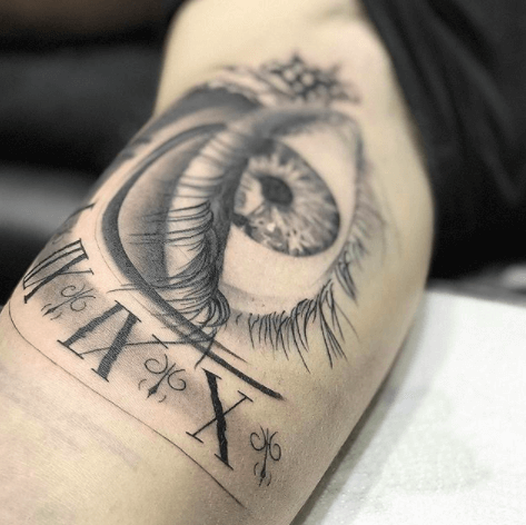 Realismo negro y gris, Héctor Mateos. Tatuaje grande en brazo de ojo con reflejo de reloj.